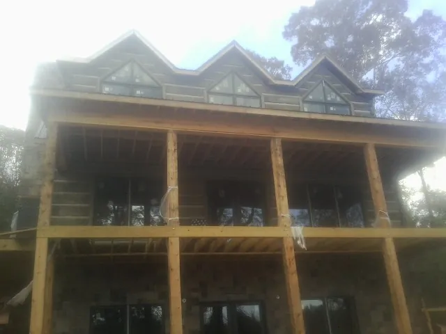 Dormers and porch framing on a large log home under construction — Roof Coating work by our crew in Walworth