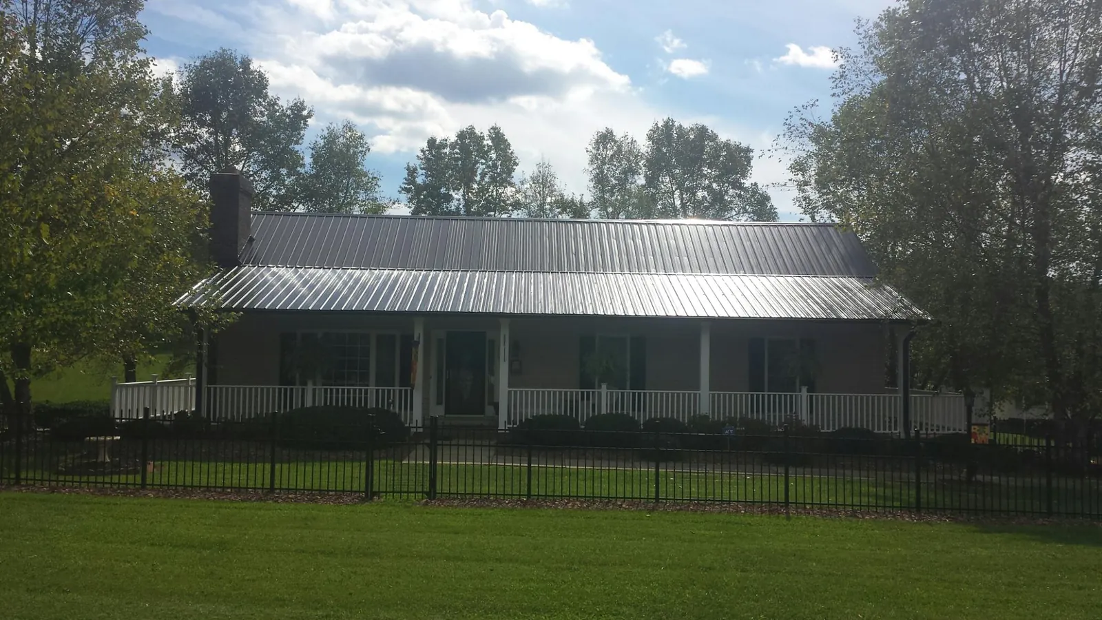 Gray metal roof on a brick ranch with a full width front porch — Gutter Guard Installation work by our crew in Walworth